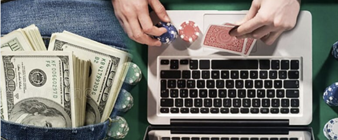 Someone playing at an online casino on their laptop with US money on left hand side